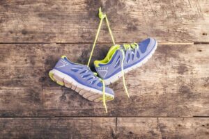 عکس کفش ورزشی آویزان از دیوار چوبی با بند کفش